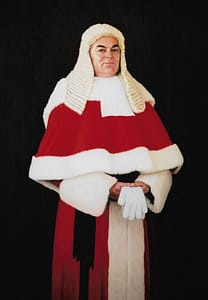 Oil painting by Josonia Palaitis depicting James Spigelman, Chief Justice of NSW standing with a pure black background holding white gloves and wearing his court wig and red and white gown
